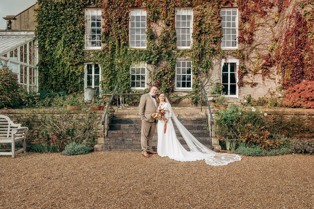 Bride and Groom at Autumn wedding at Pennard house in front of house